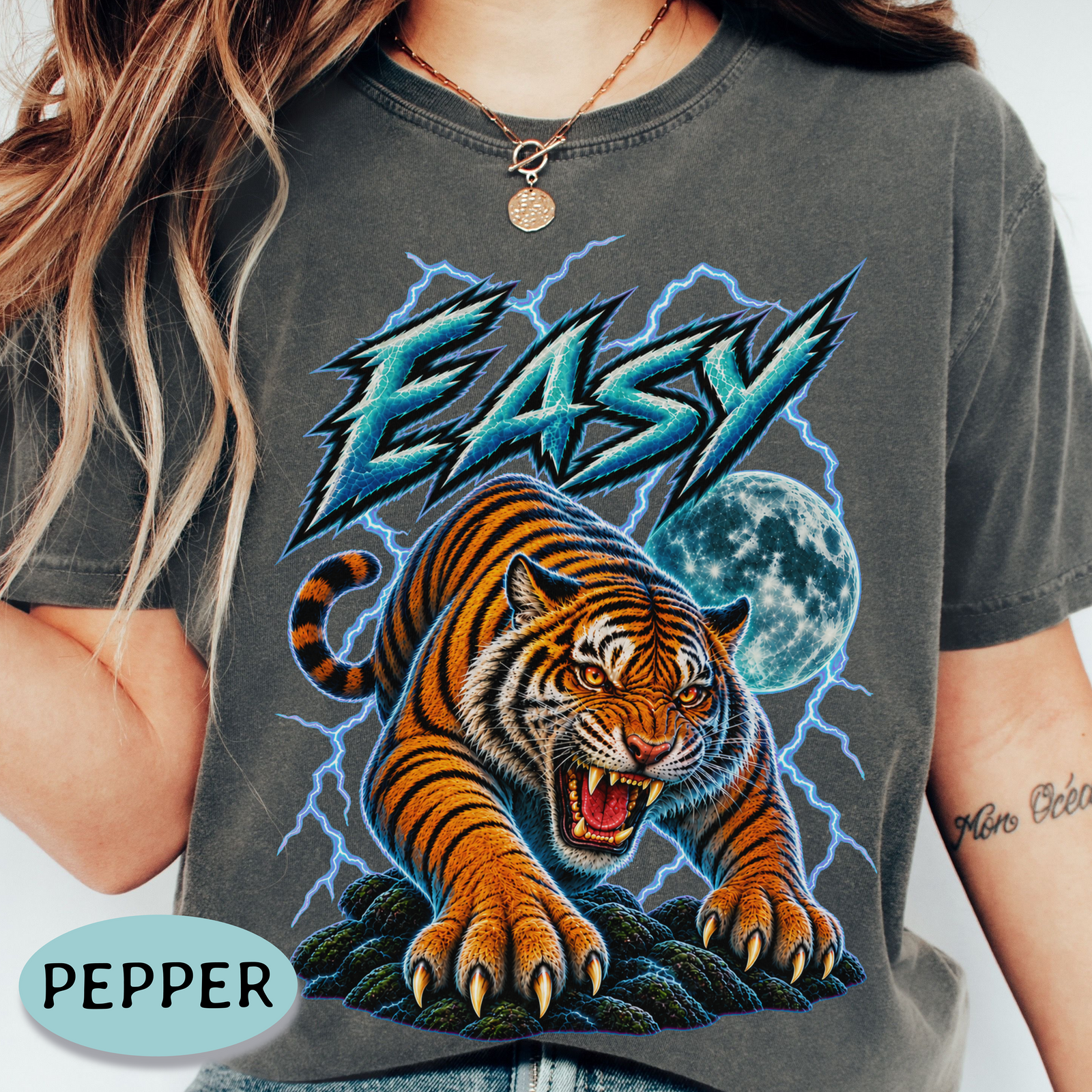 A person wearing a faded charcoal gray graphic T-shirt with a large tiger, lightning, moon, and the word “EASY” printed on the front. 
