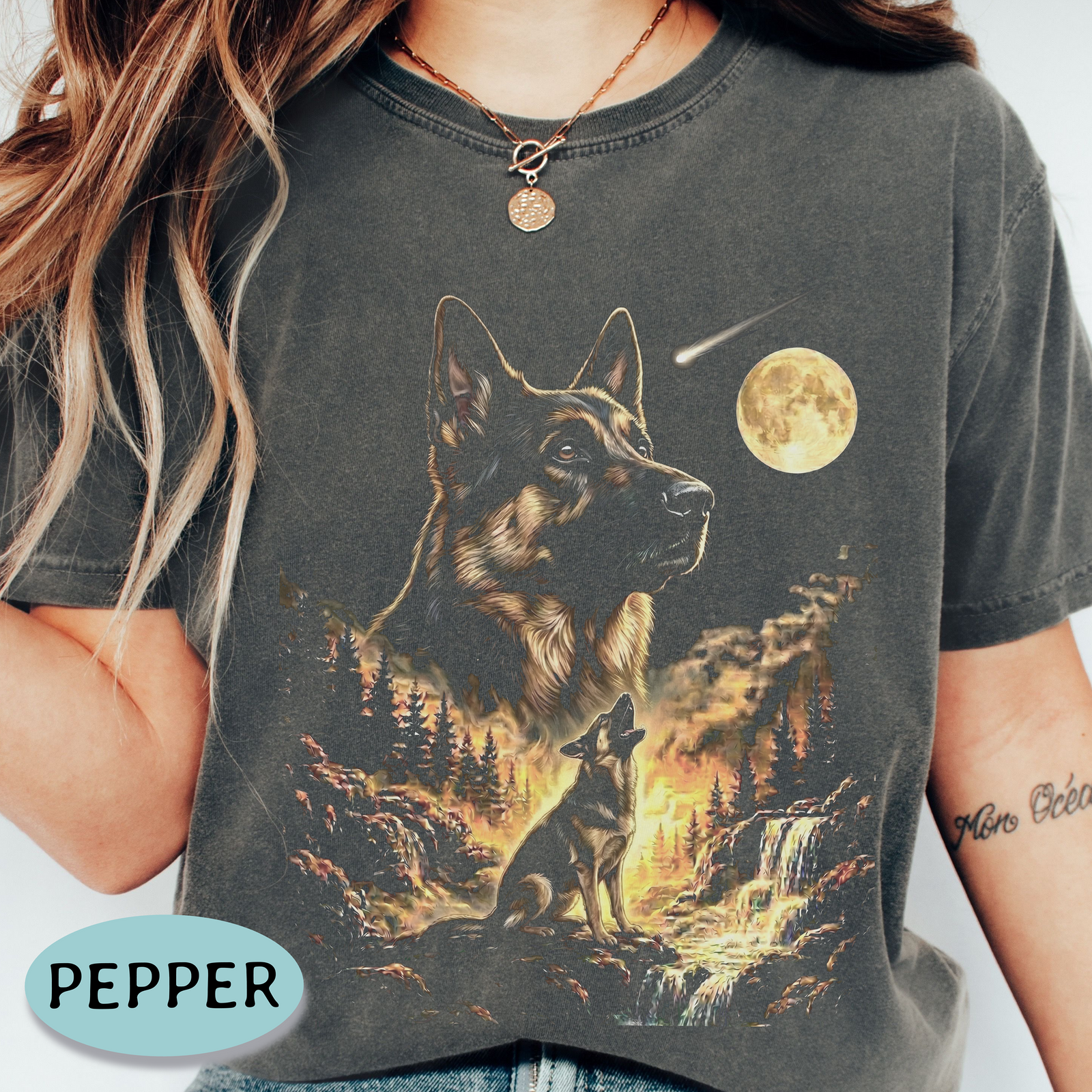A person wearing a dark charcoal graphic T-shirt featuring a large German Shepherd and a smaller dog in a moonlit mountain scene. The shirt has a faded wash finish.